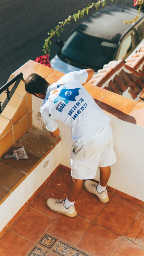 Pintor de Brochaman pintando la barandilla de una terraza