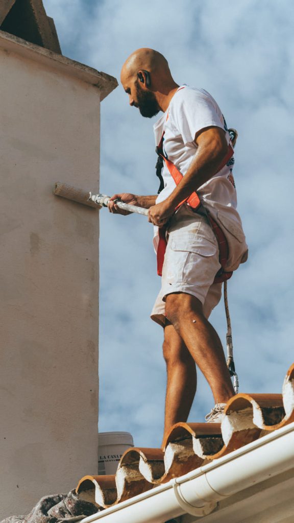 Pintor de Brochaman trabajando en la chimenea de un tejado